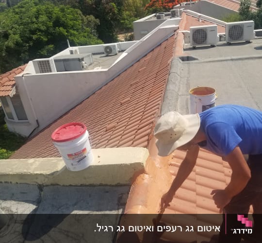אדם מורח חומר על גג רעפים עם מברשת